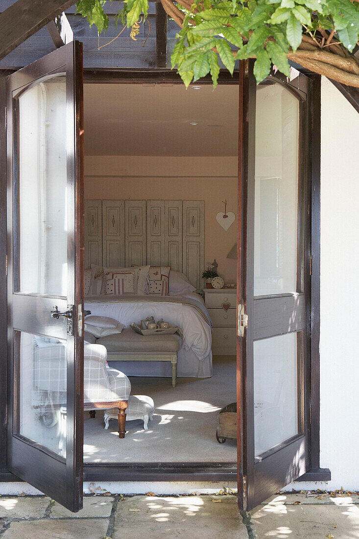 View through double doors into bedroom with folding screen headboard