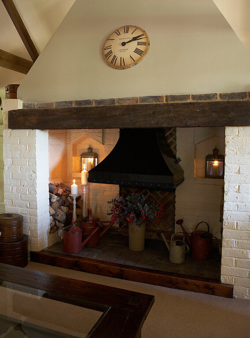 Blumenarrangement und Gießkannen im Kamin eines umgebauten Bauernhauses