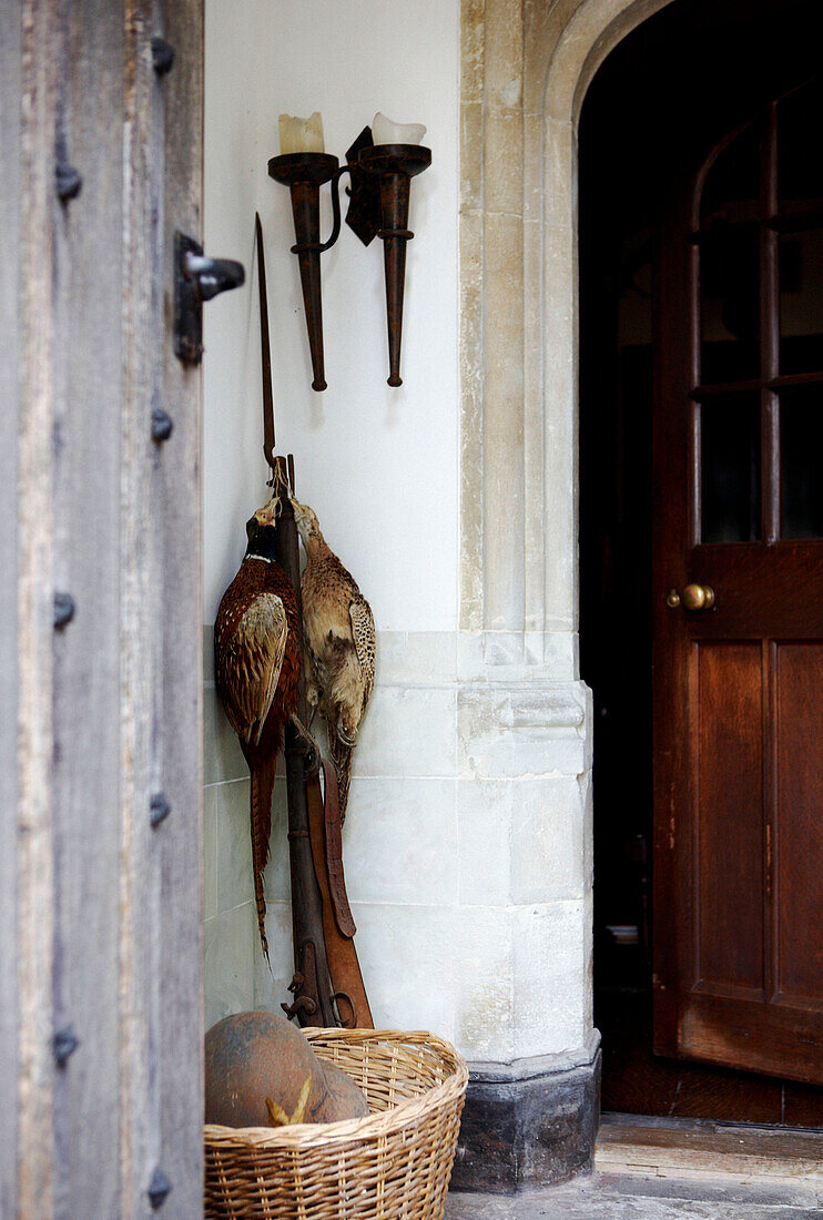 Fasane hängen mit einem Gewehr an der Eingangstür eines elisabethanischen Herrenhauses in Kent, das unter Denkmalschutz steht (Grade I)