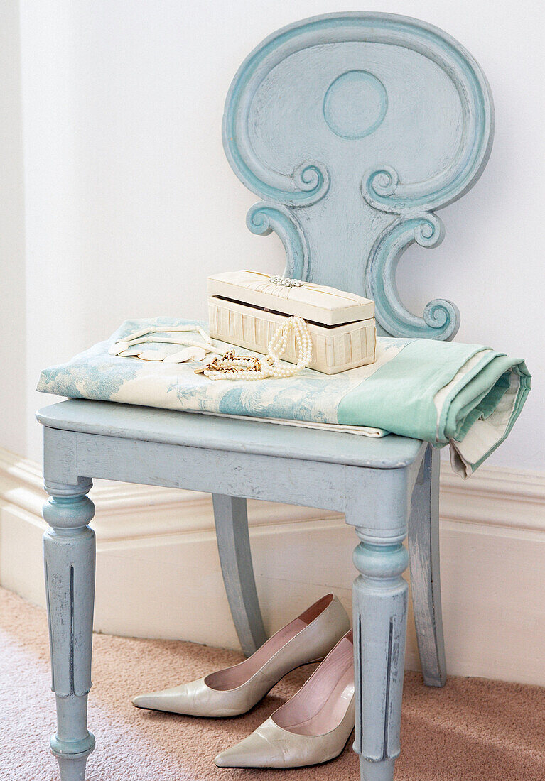 Jewellery box and string of pearls on painted chair with a pair of high heeled shoes 