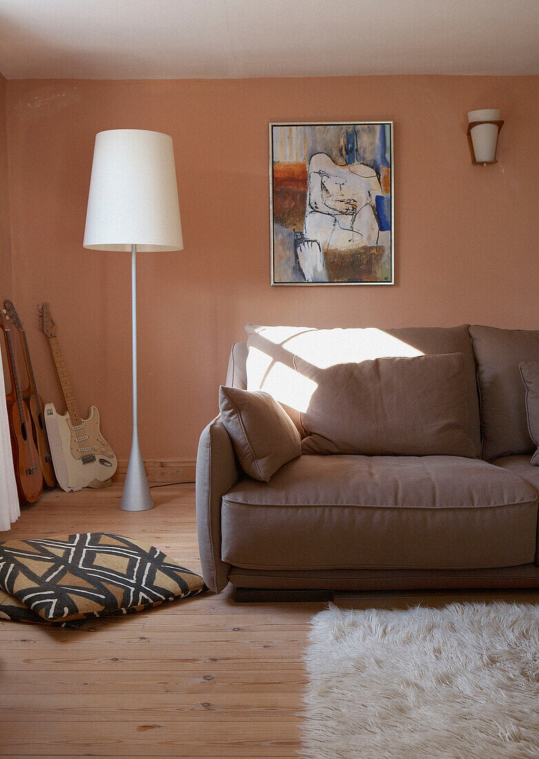 Hellbraunes Sofa in pfirsichfarbenem Wohnzimmer mit übergroßer Stehlampe