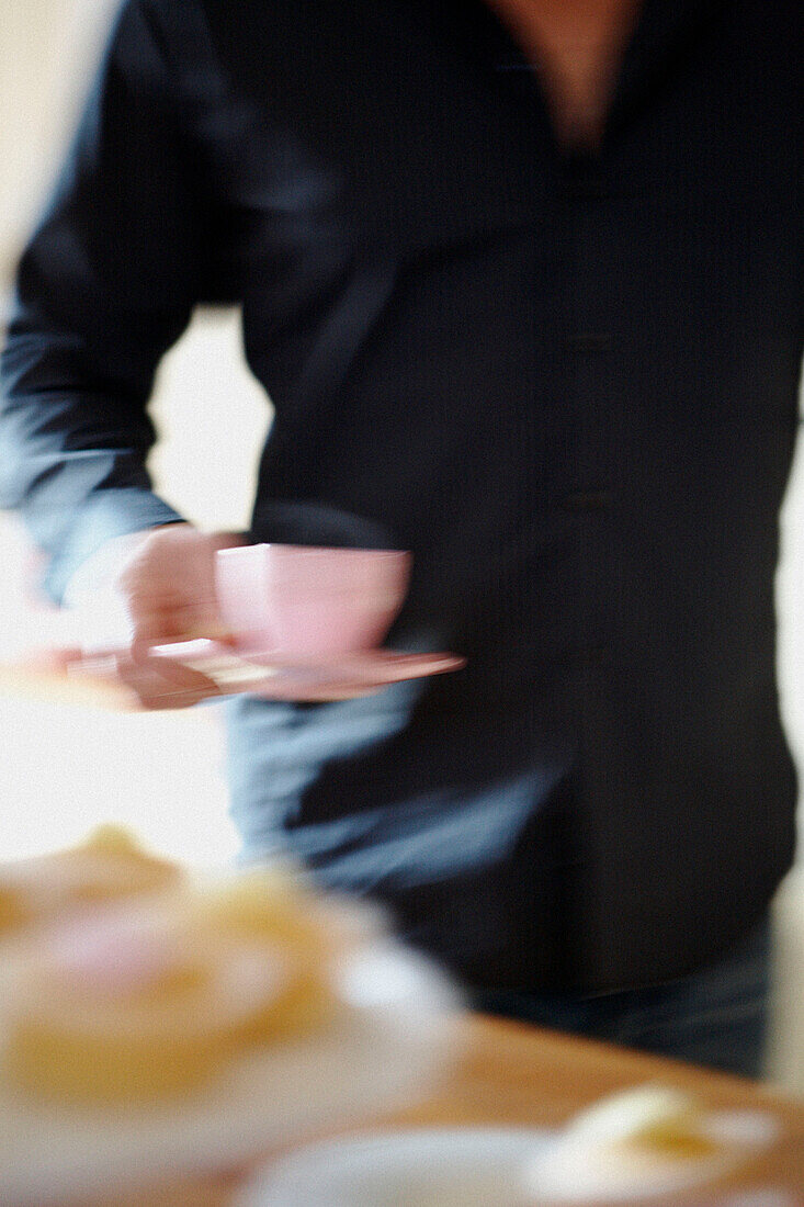 Mann im blauen Hemd trägt eine heiße Tasse Tee