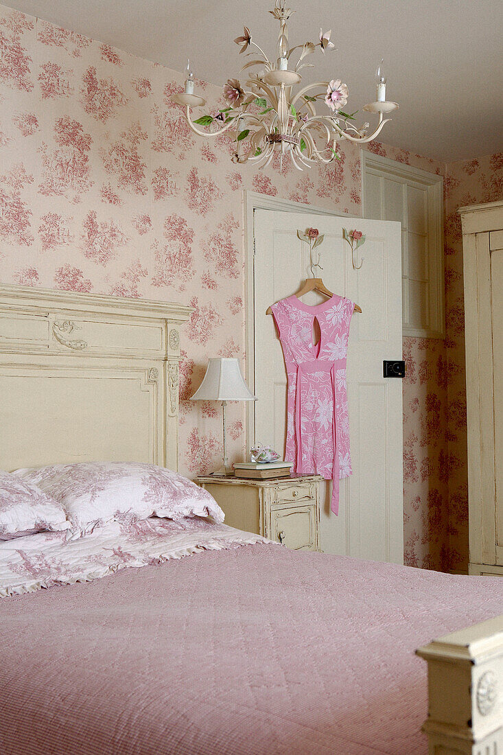 Rosa Kleid hängt an der Rückseite der Tür in einem mit rosa Blumentapete tapezierten Zimmer