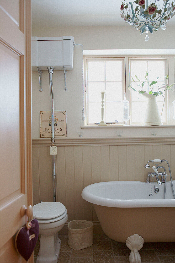 Wall mounted cistern in sunlit panelled bathroom
