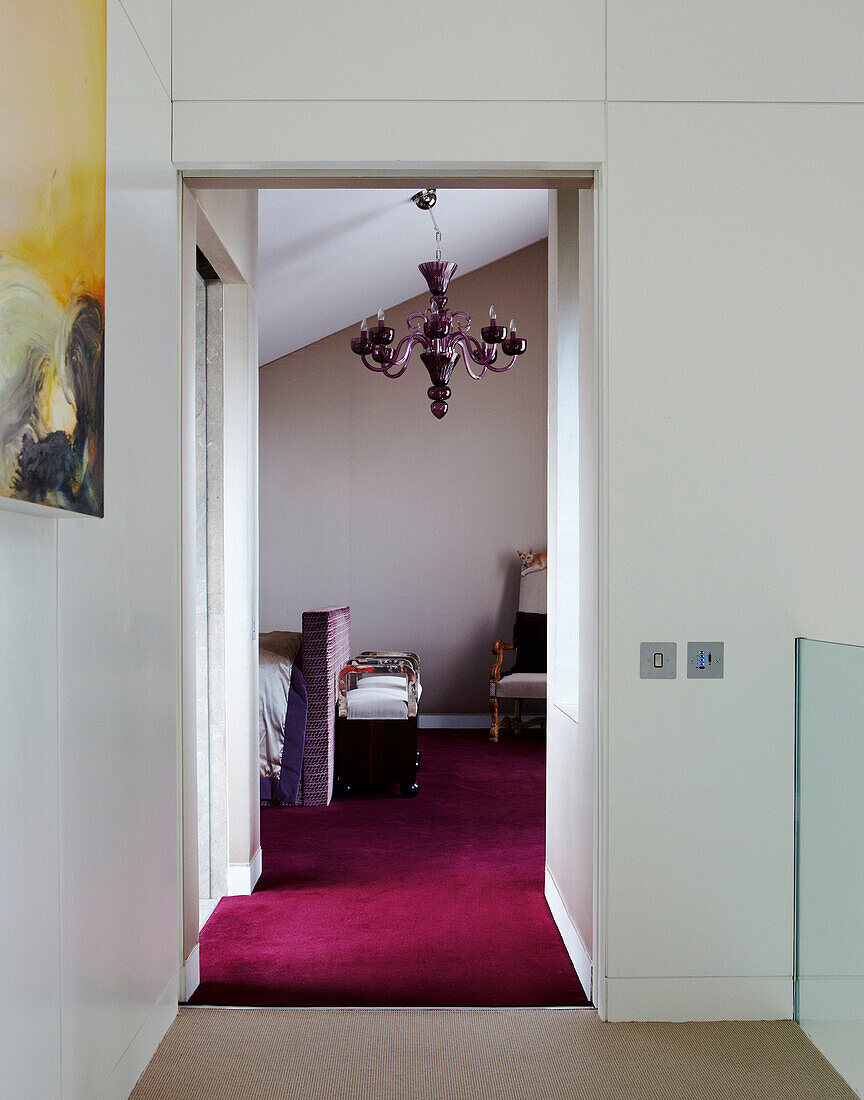 View through doorway to bedroom with fuscia carpet and purple chandelier