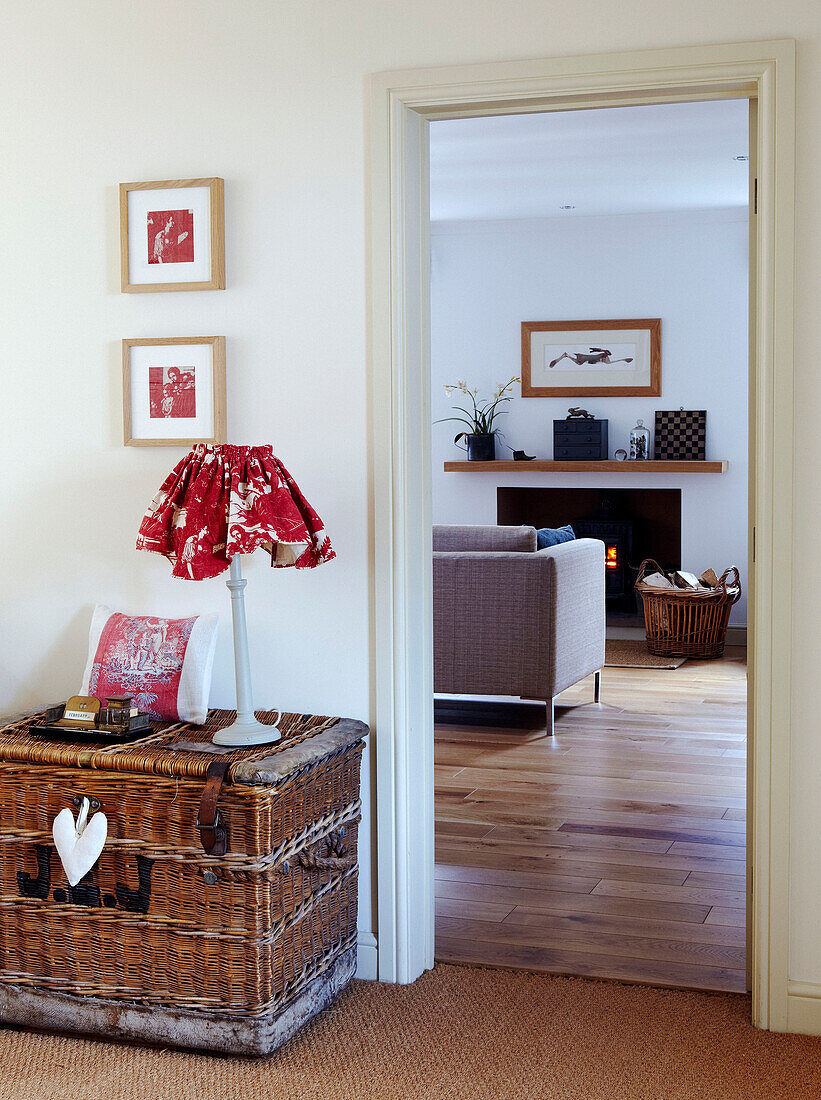 Lampe auf Wäschekorb im Flur mit Blick durch die Tür zum Wohnzimmer mit Holzkorb