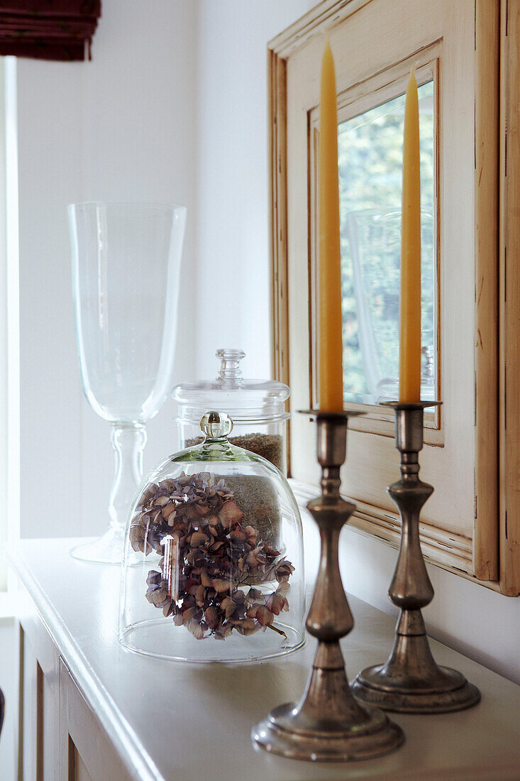 Silberne Kerzenständer und Glaswaren auf Regal mit bemaltem Spiegelrahmen