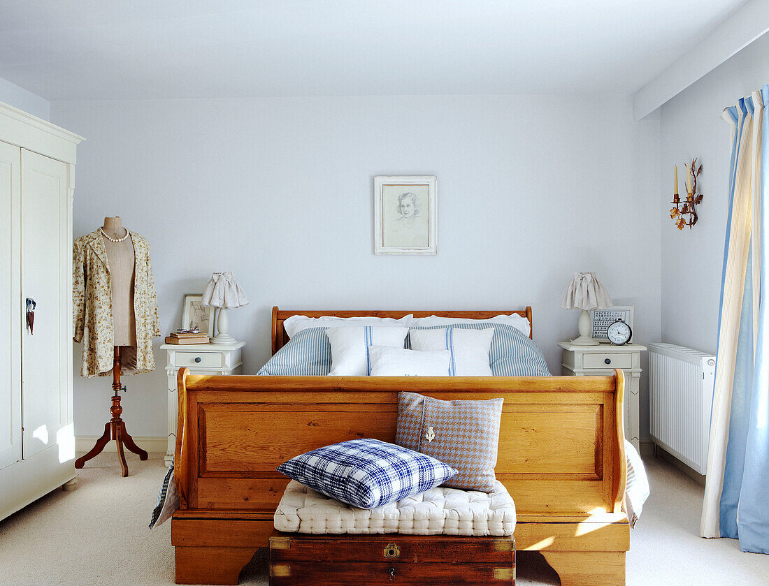 Holzbett in pastellblauem Schlafzimmer mit Schaufensterpuppe