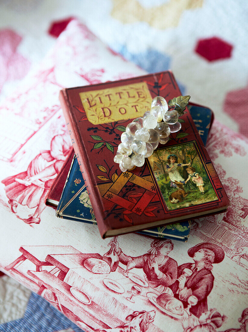 Vintage-Kinderbücher und Brosche auf gemusterter Tischplatte