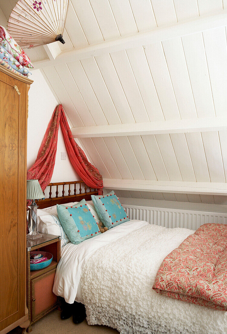 Single bed under panelled attic ceiling of Edwardian school house conversion