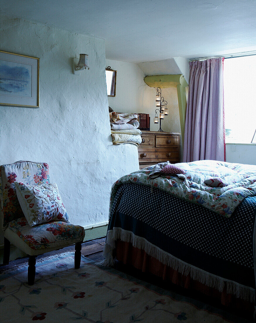 Quilt covers and embroidery in whitewashed 16th Century Welsh farmhouse bedroom