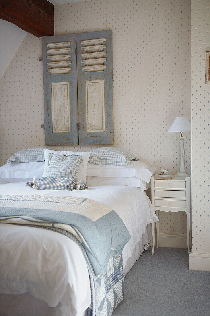 Pastellblaue Bettbezüge auf einem Doppelbett mit geretteten Fensterläden