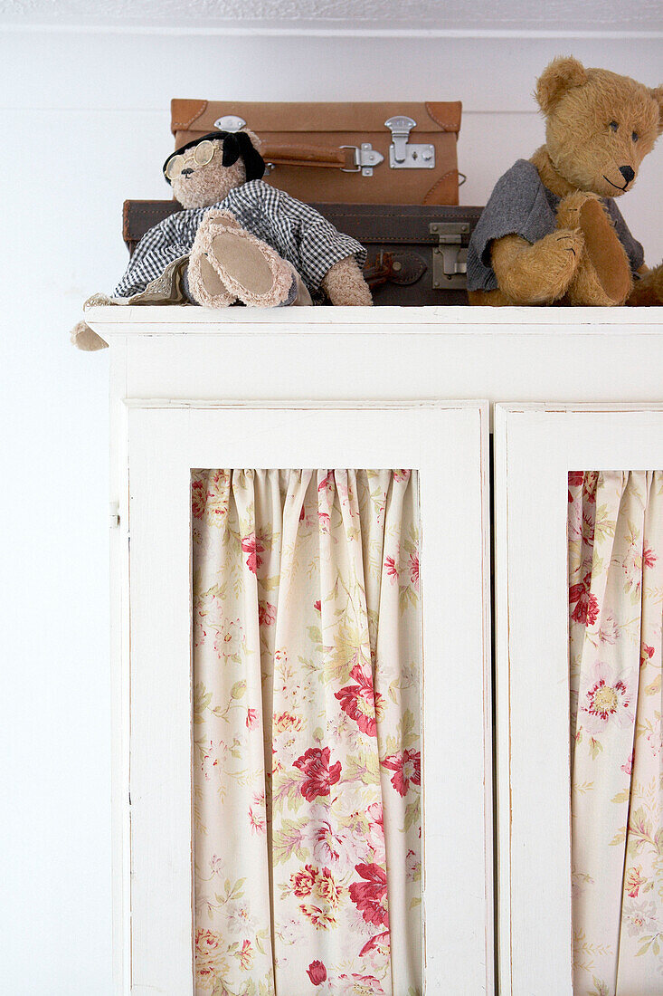 Teddy bears and suitcases on top of painted wardrobe
