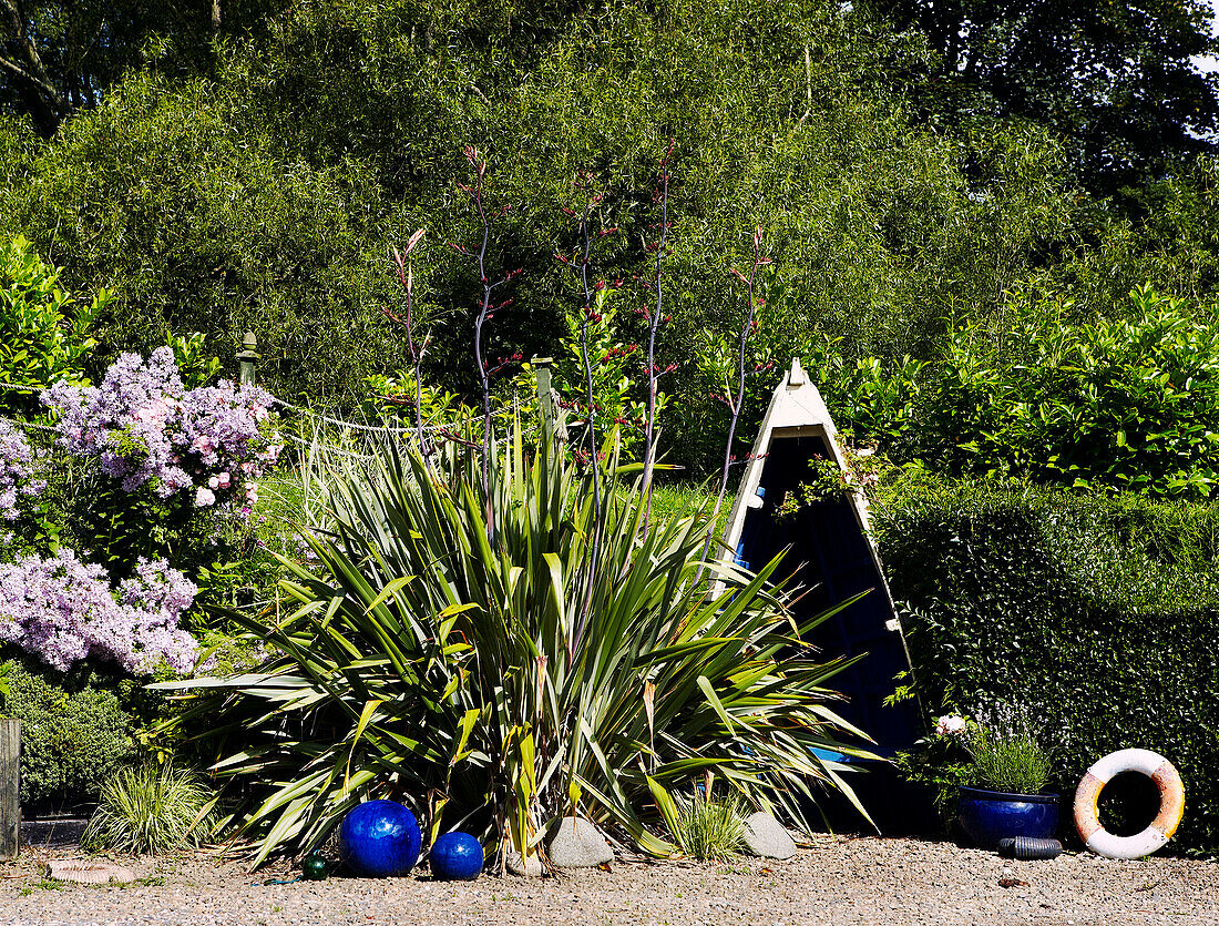 Sawn boat and plant in garden with gravel bed