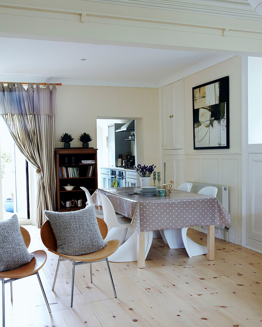 Open plan dining room with spotted tablecloth and wooden floor