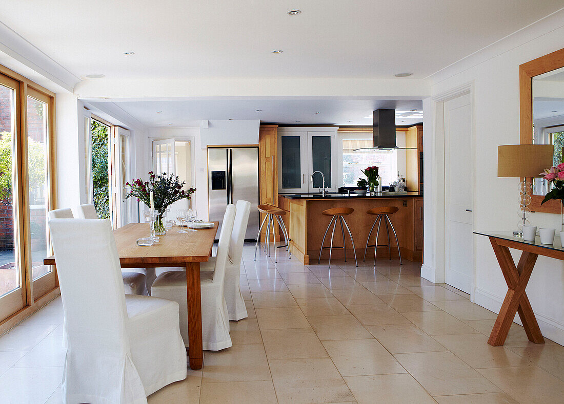 Open plan dining room with white slip covered chairs at table