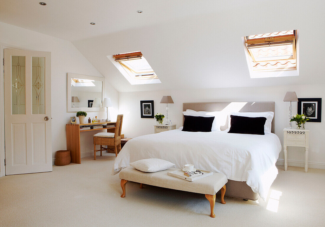 Attic bedroom with black cushions on white bed
