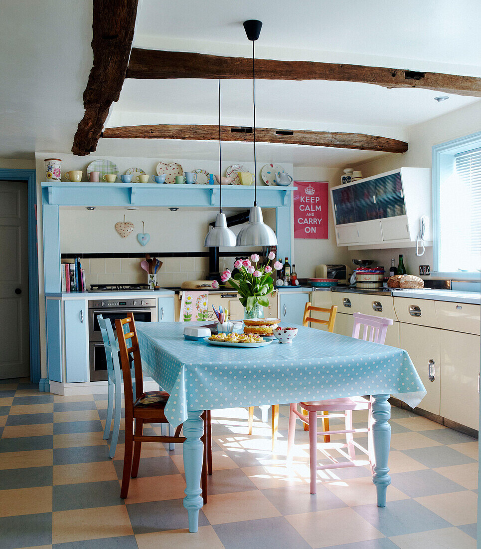 Küche aus den 1950er Jahren mit Balkendecke und pastellblau getupfter Tischdecke