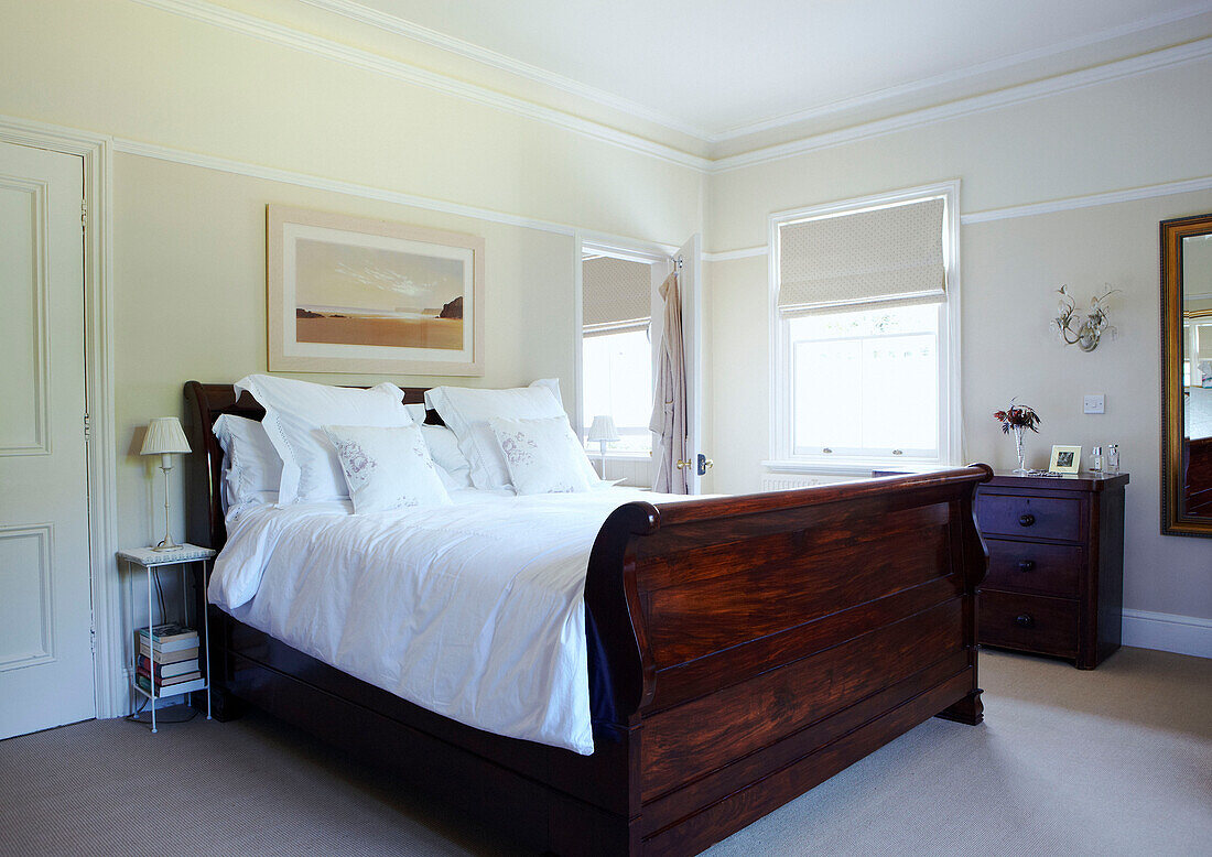Polished wooden double bed with white bed linen