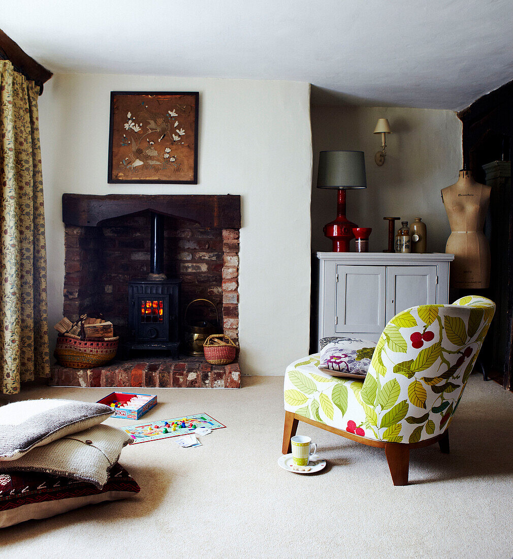 Holzofen im Wohnzimmer eines Cottage in Devon mit geblümtem Stuhl