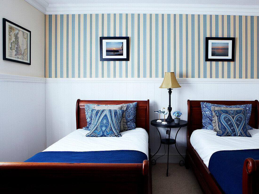 Twin beds in room with striped wallpaper and tongue and groove panelling