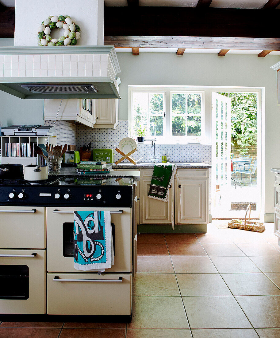 Herd mit Dunstabzug in einer gefliesten Küche mit sonnenbeschienener Hintertür
