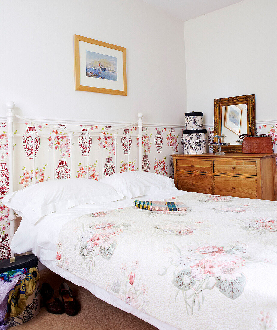 Artwork above bed with patterned panelling and wooden chest of drawers