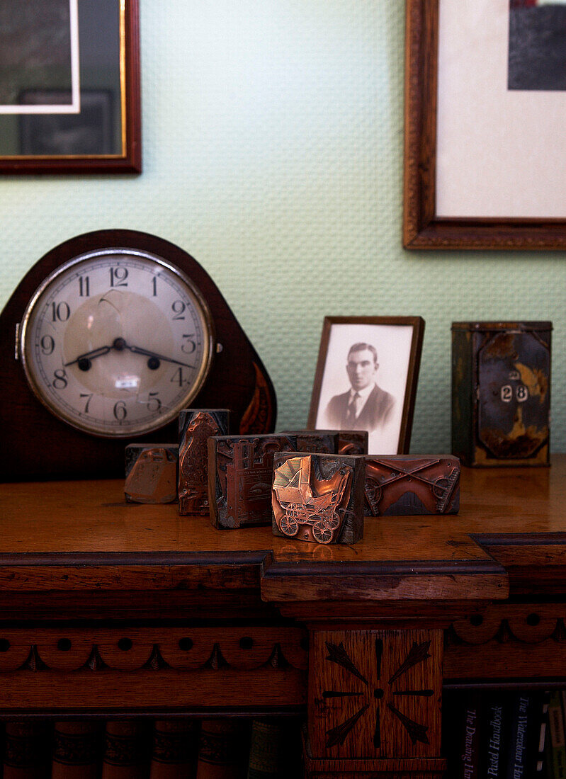 Gruppe von Objekten, darunter eine Manteluhr und Fotos auf einem Holztisch