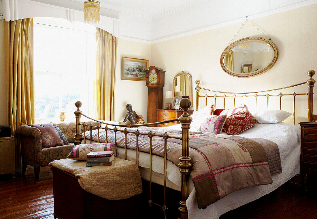 Schlafzimmer mit Vintage-Messingbettgestell und goldfarbenen Vorhängen