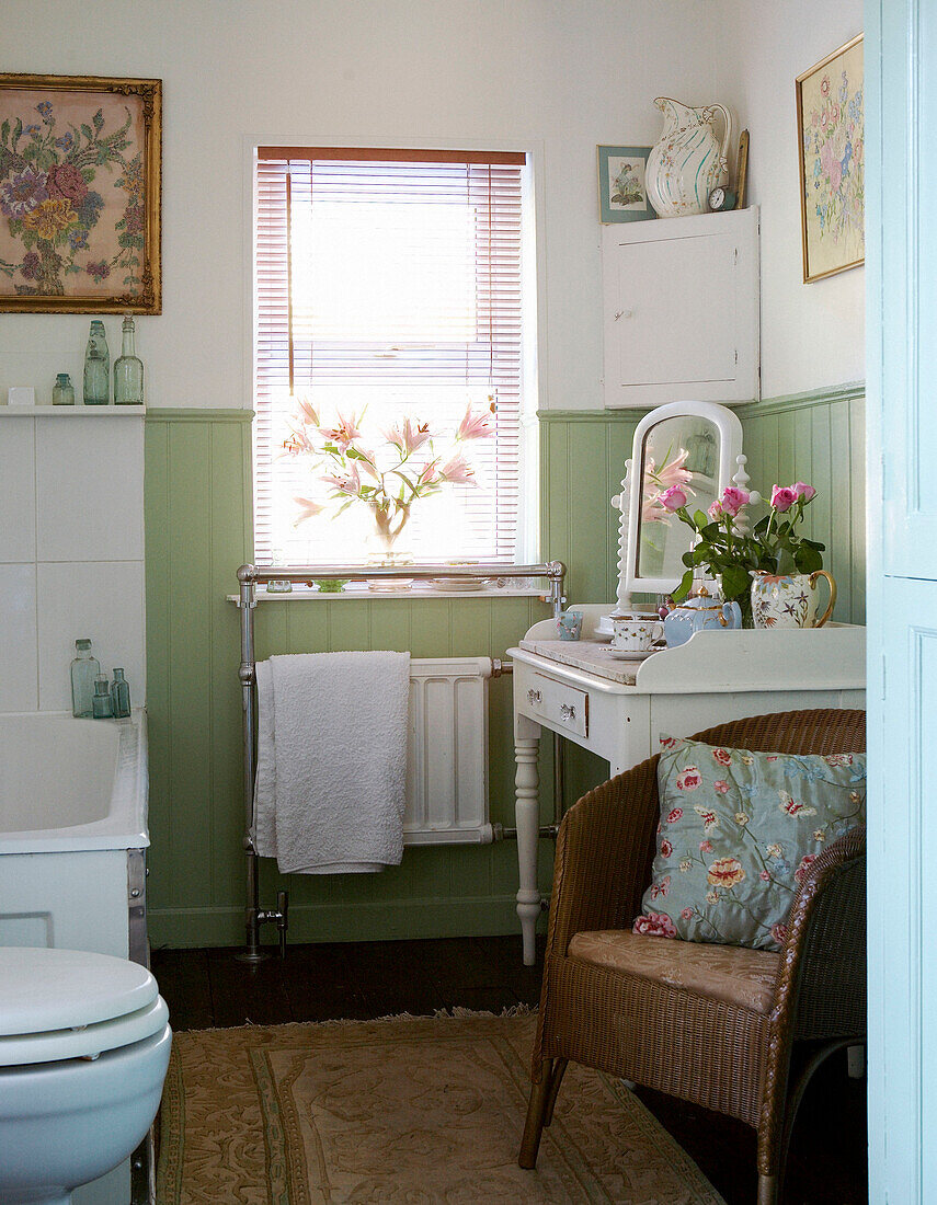 Bathroom with vintage table and mirror and pale green wall panelling