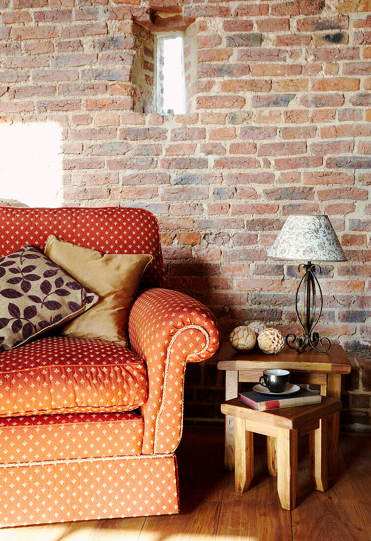 orange polka dot sofa with occasional table against exposed brick wall