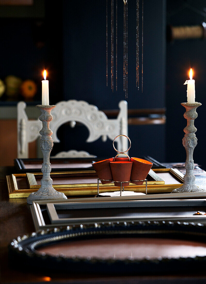 Lit candles and empty picture frames on dining table