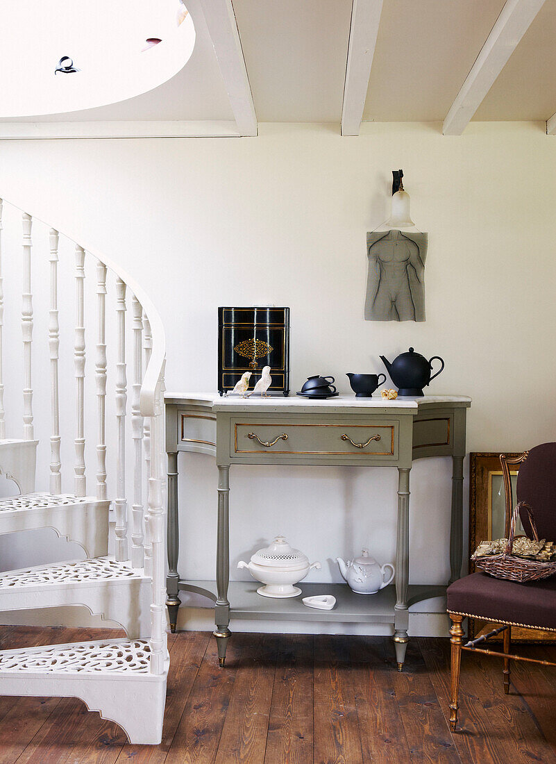 Side table and white spiral staircase in country cottage