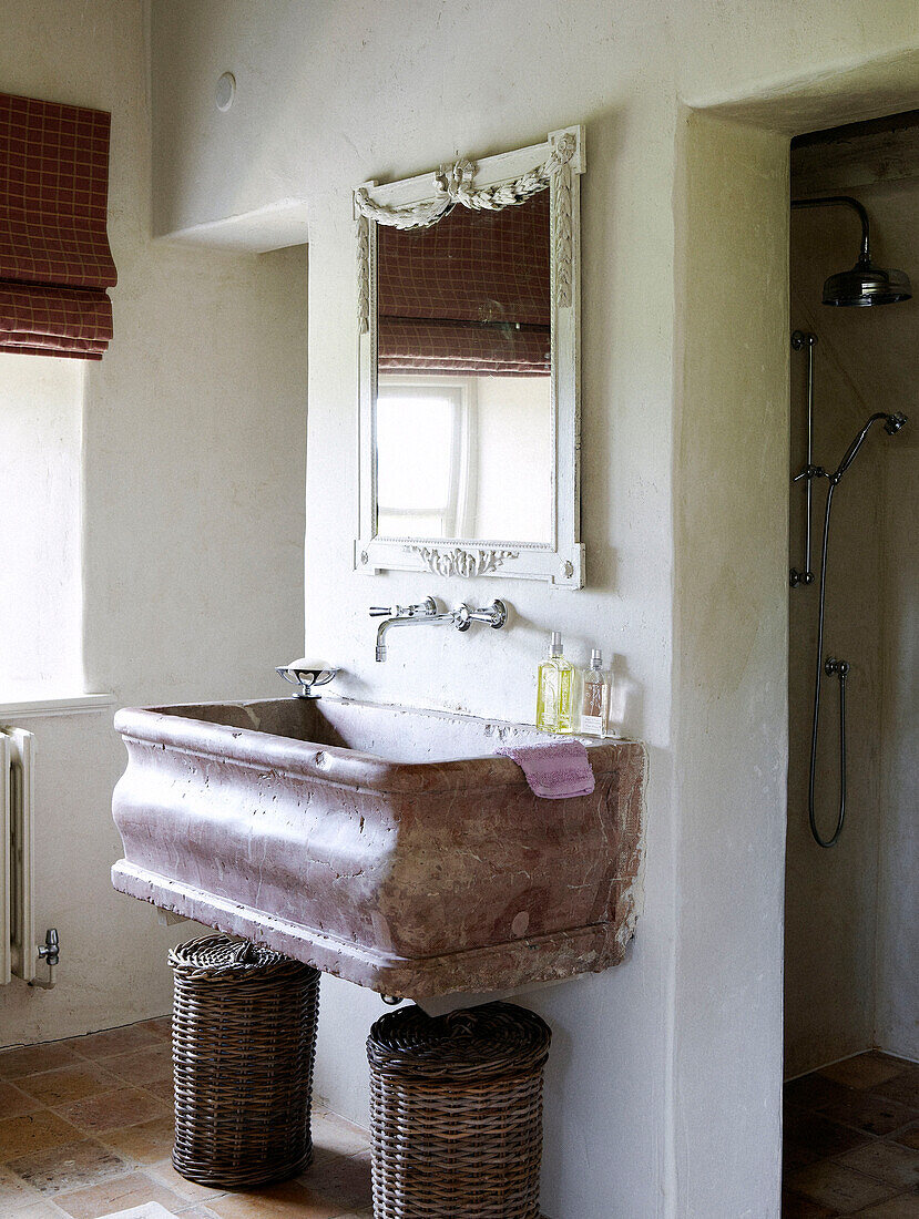 Mirror above marble wash basin with laundry baskets in country home