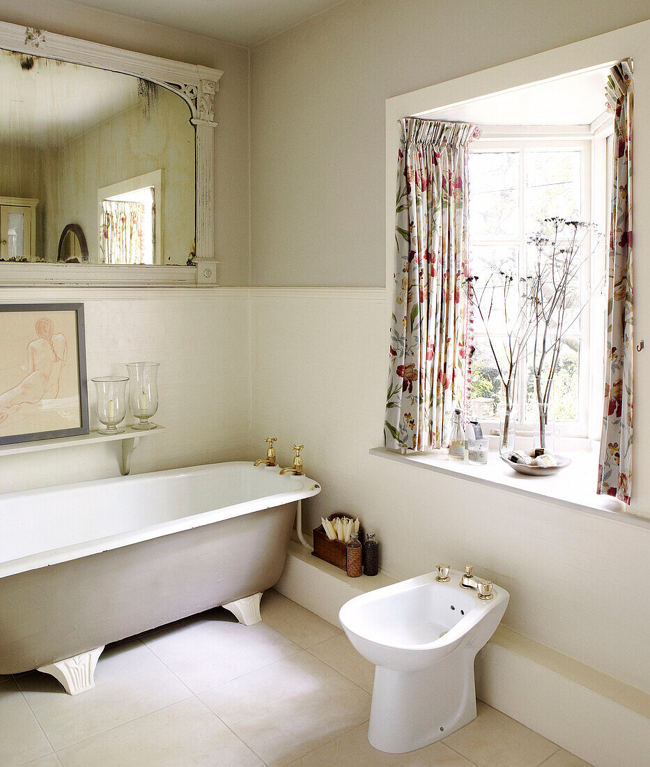 Bidet und freistehende Badewanne im Badezimmer mit floral gemusterten Vorhängen am Erkerfenster