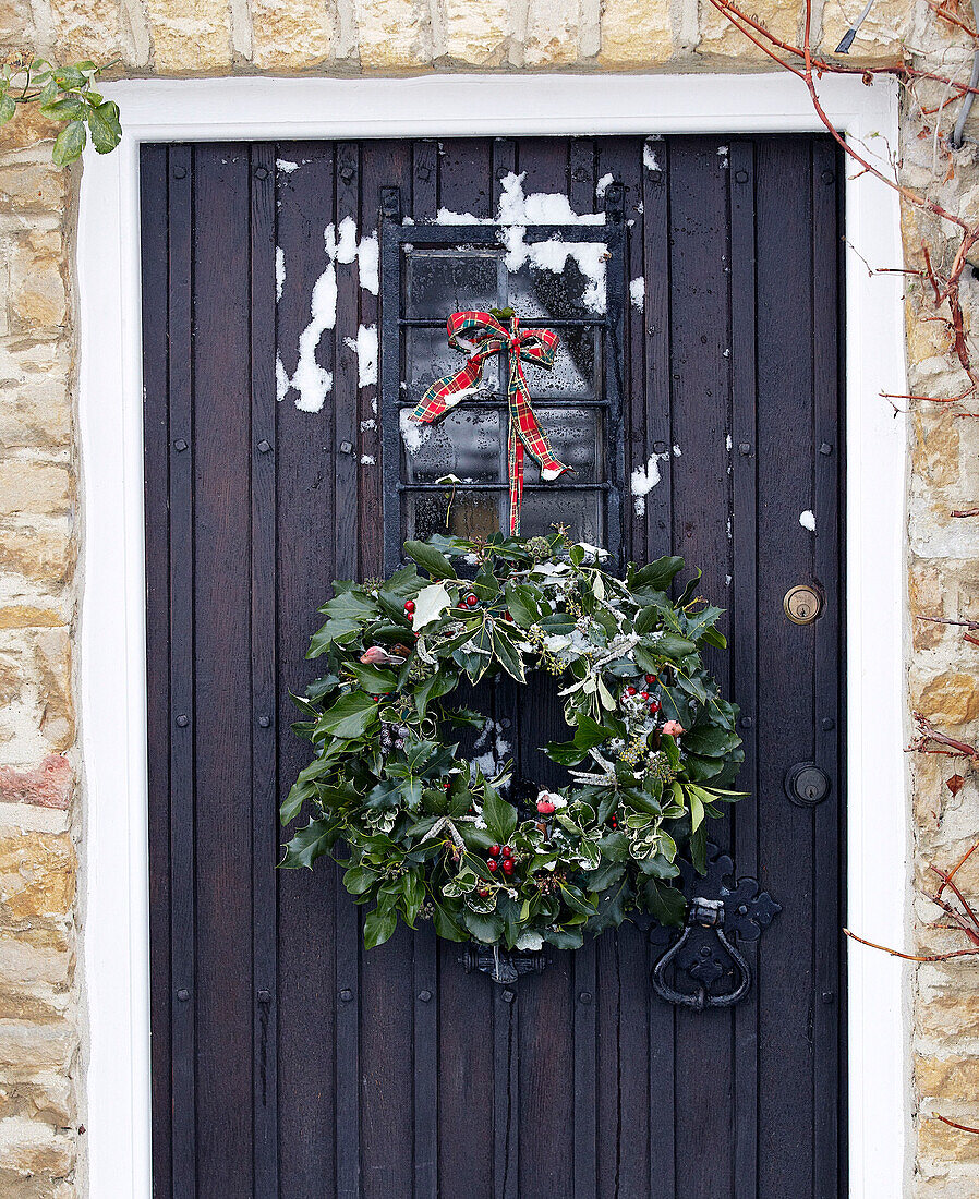 Christmas wreath hanging on black front door