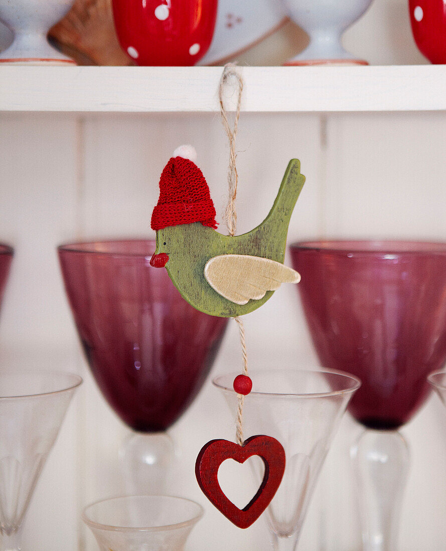 Christmas bird decoration and coloured glassware on kitchen dresser