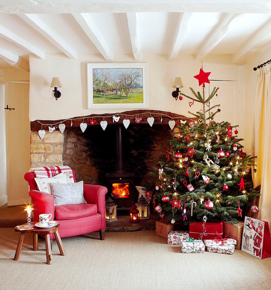 Christmas tree and red armchair at open fireplace with heart shaped decorations