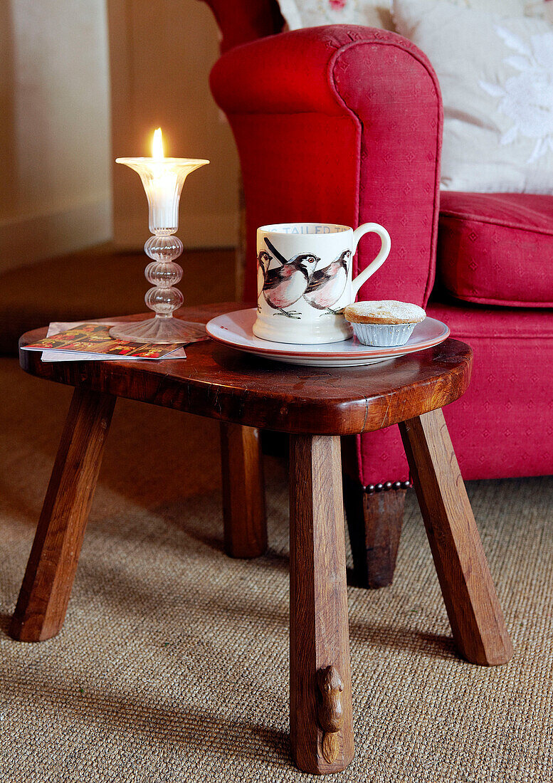 Mince pie and cup on side table with lit candle