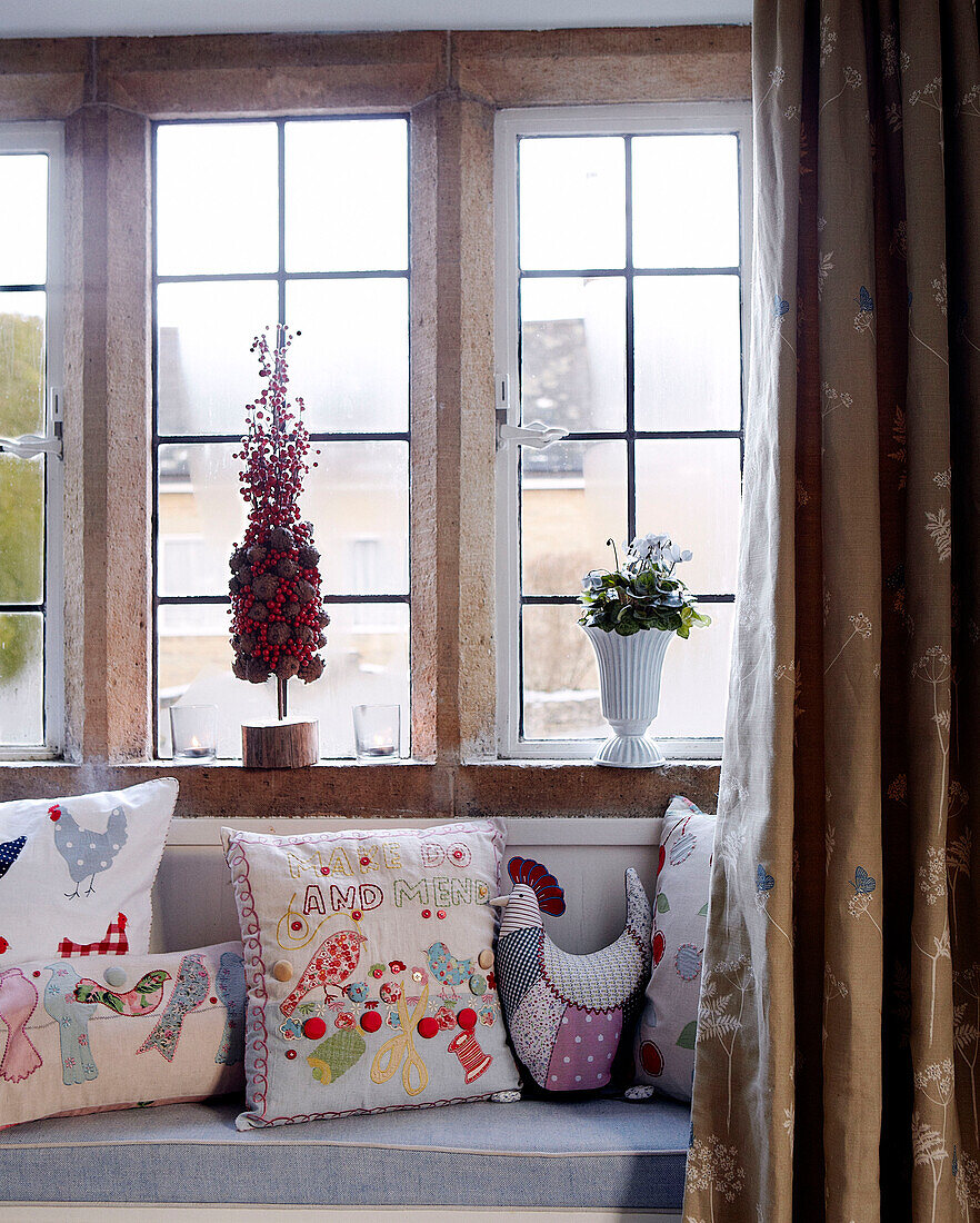 Embroidered cushions on window seat of country home