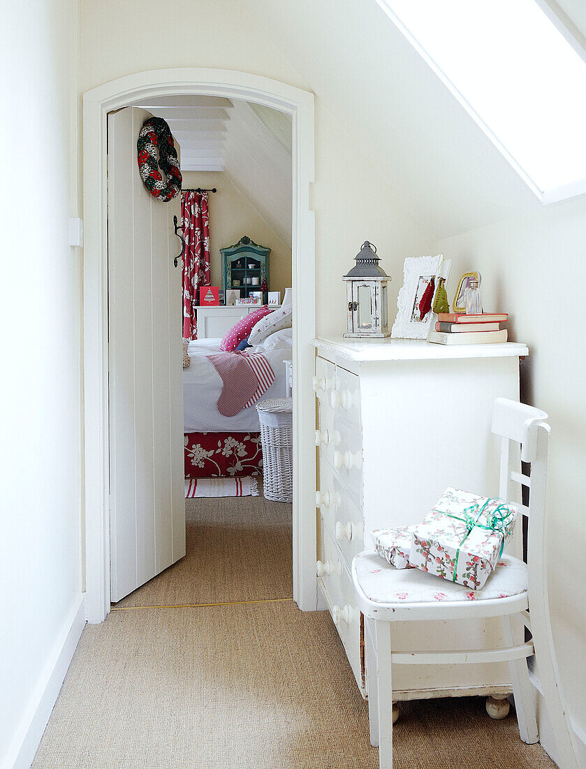 Gift wrapped presents on chair with painted dresser in hallway to bedroom