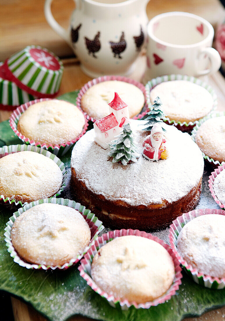 Sponge cake with Christmas figurines and mince pies with icing sugar