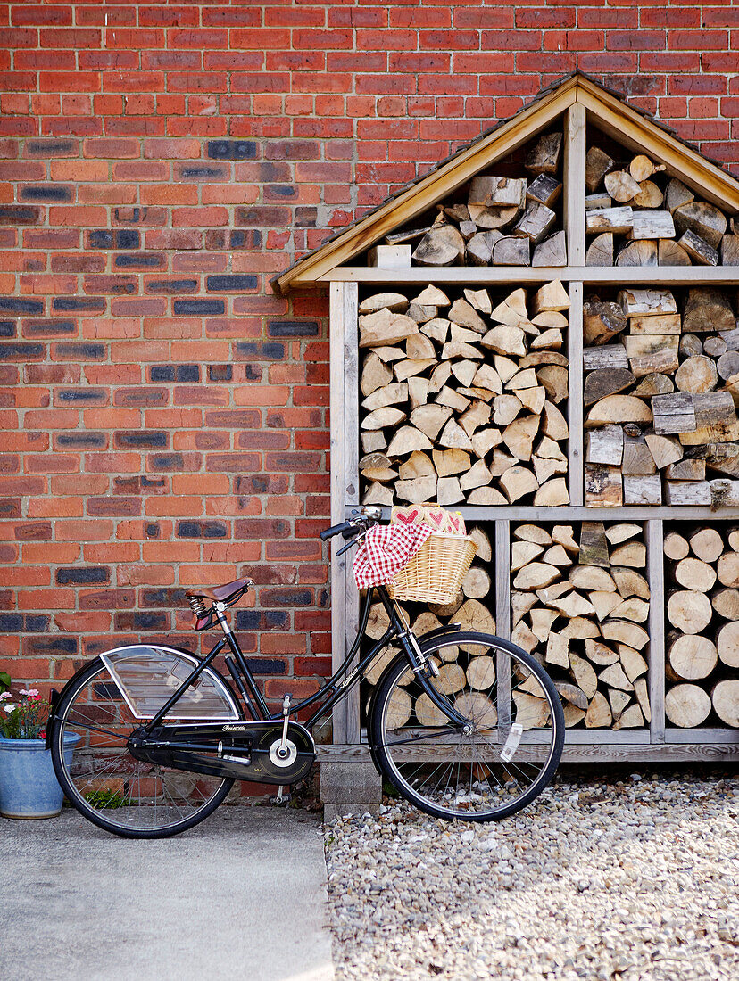 Fahrrad geparkt mit geschnittenem Brennholz an einer Backsteinfassade