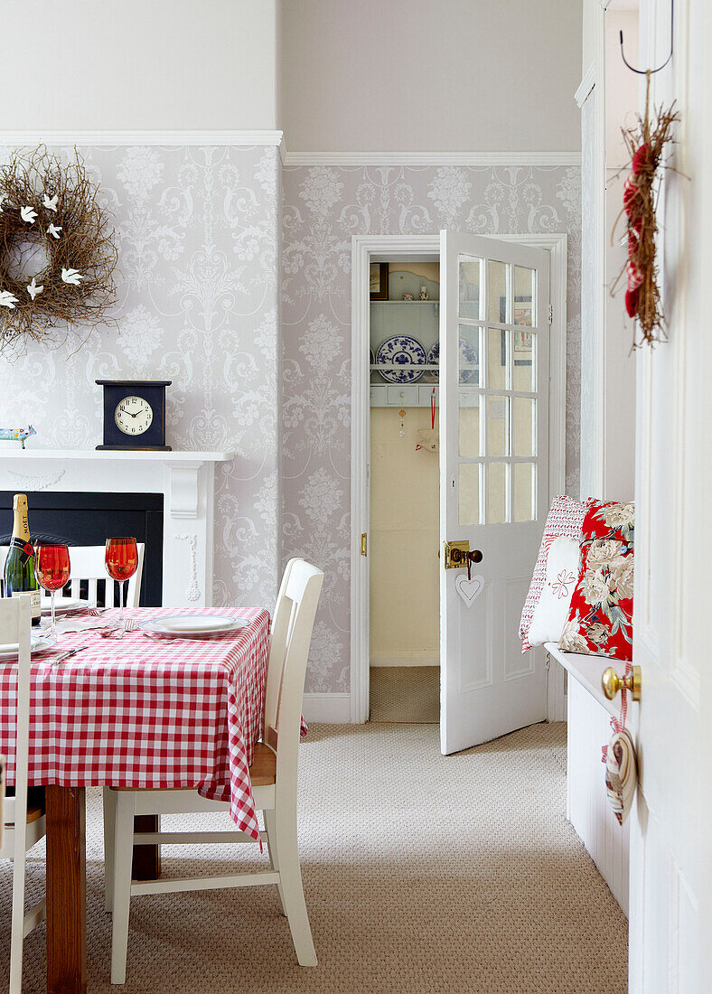 Checked tablecloth on table with grey patterned wallpaper in dining room family home