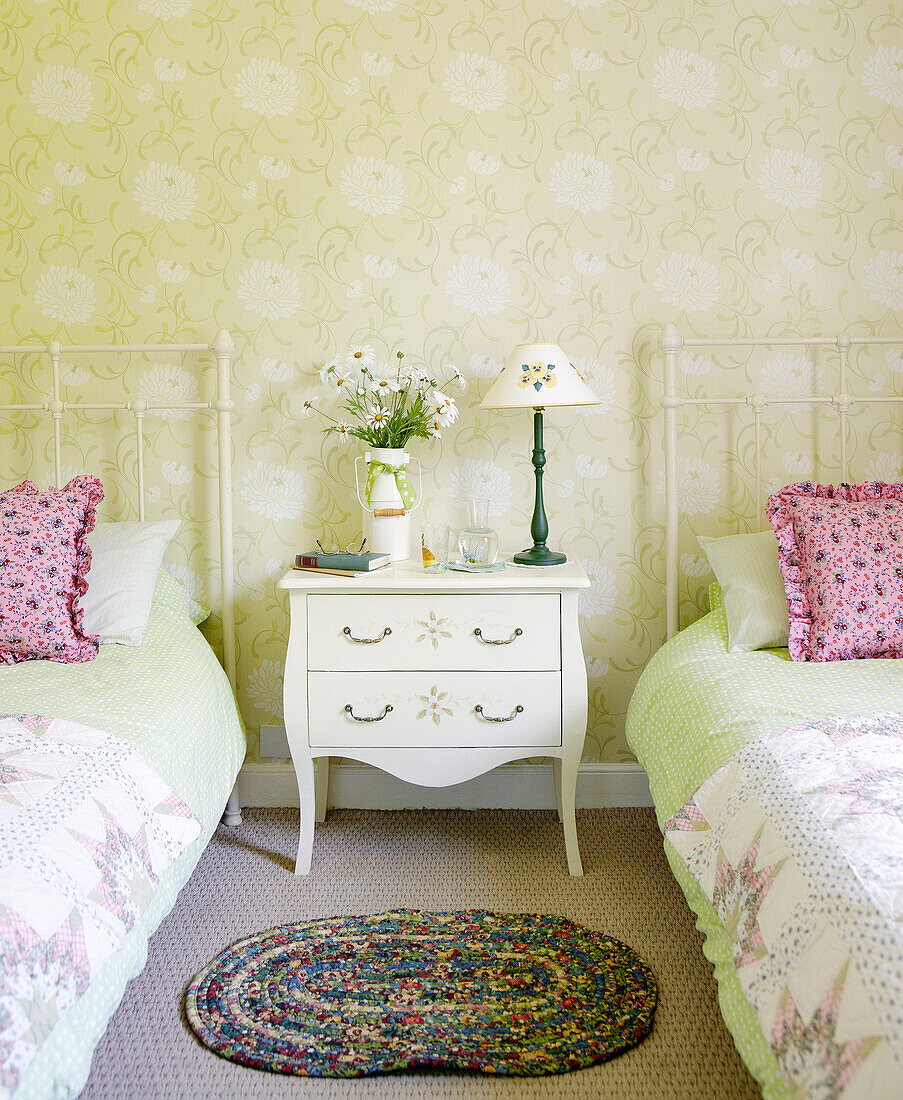 Twin beds separated by rug and miniature bedside table