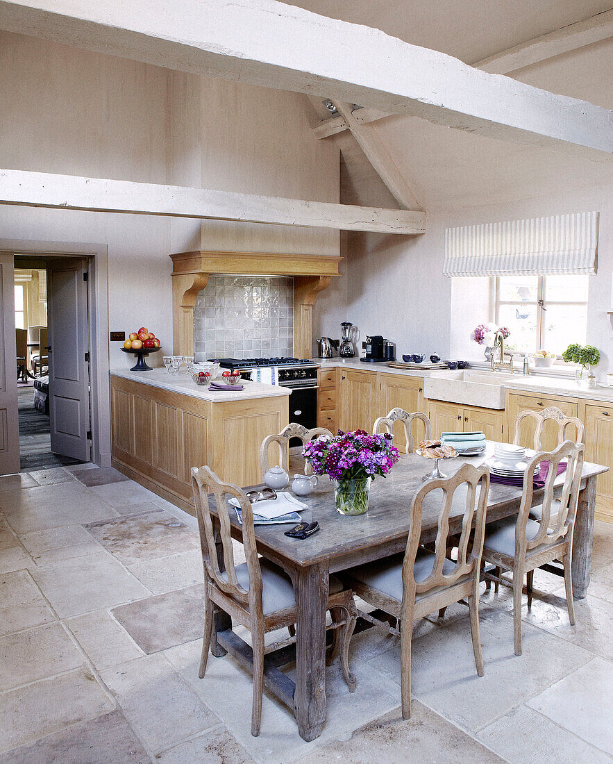Sunlit beamed kitchen with cut flowers in country home