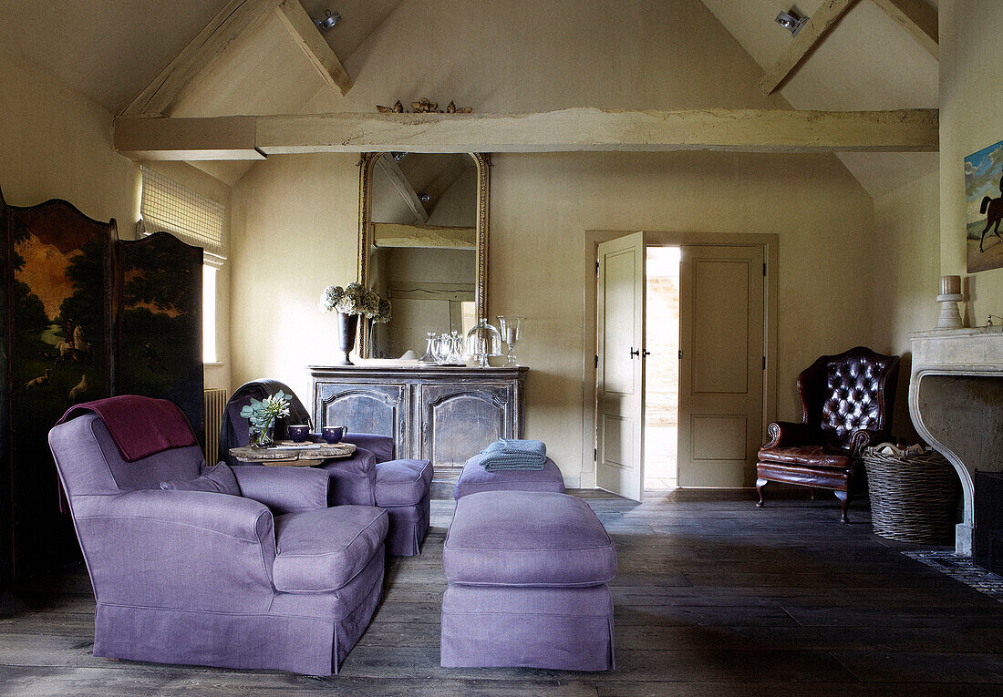 Fliederfarbene Sessel mit Fußstützen und Faltwand im Wohnzimmer eines Landhauses
