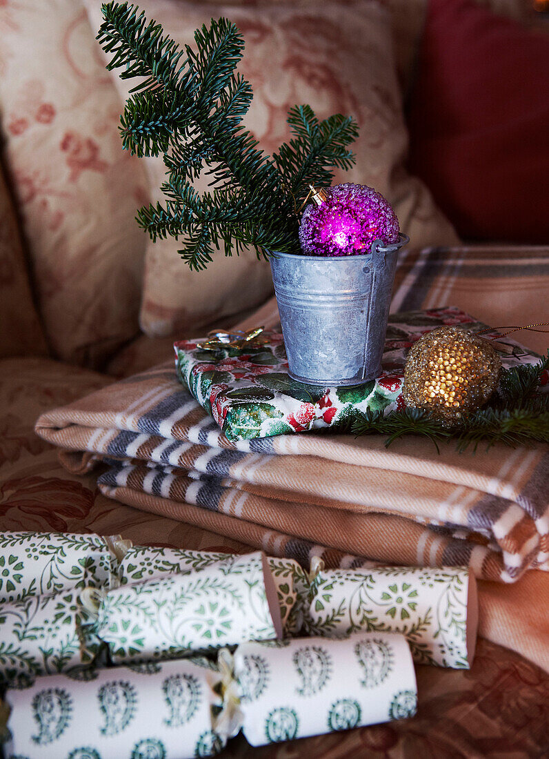 Sprig of pine and Christmas baubles with crackers and folded tablecloth