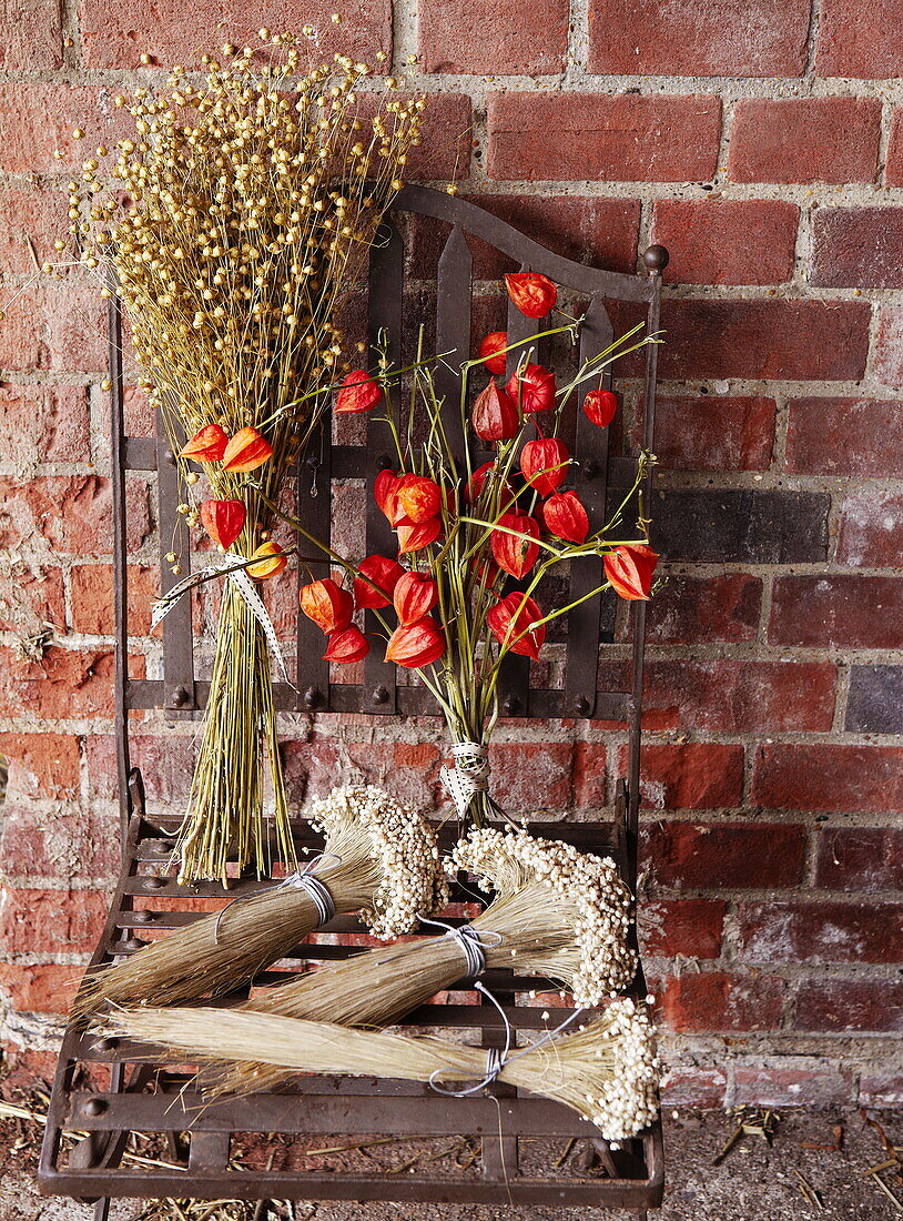 Dried flowers and metal chair against brick wall in Essex England UK