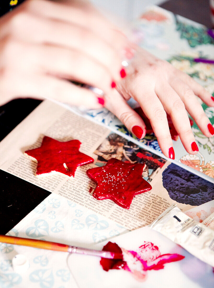 Woman painting red star-shaped Christmas decorations